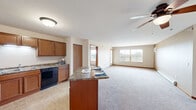Located at 4727 Arbor Crossing SE in Alexandria, Minnesota, this single-floor, three-bedroom, two-bathroom home offers a well-organized and functional layout. The kitchen is a standout feature, equipped with warm medium-toned wood cabinetry, granite-style laminate countertops, black appliances including a refrigerator, range, microwave, and dishwasher, as well as a central island that provides additional prep and dining space. Tile flooring grounds the kitchen area, which flows naturally into the living space. The three bedrooms are carpeted and feature ceiling fans with light fixtures, baseboard heating, and windows that let in natural light with views of the surrounding green landscape. The spacious primary bedroom also includes a wall-mounted air conditioning unit for added comfort. Both bathrooms are finished with tile flooring, wood-toned vanity cabinetry, and light countertops; one bathroom features a tub-shower combination. A dedicated laundry room and a closet with wire shelving add practical storage and utility to the home. Warm wood trim and neutral wall tones carry throughout, giving the space a cohesive and understated character.