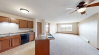 Located at 4727 Arbor Crossing SE in Alexandria, Minnesota, this single-floor, three-bedroom, two-bathroom home offers a well-organized and functional layout. The kitchen is a standout feature, equipped with warm medium-toned wood cabinetry, granite-style laminate countertops, black appliances including a refrigerator, range, microwave, and dishwasher, as well as a central island that provides additional prep and dining space. Tile flooring grounds the kitchen area, which flows naturally into the living space. The three bedrooms are carpeted and feature ceiling fans with light fixtures, baseboard heating, and windows that let in natural light with views of the surrounding green landscape. The spacious primary bedroom also includes a wall-mounted air conditioning unit for added comfort. Both bathrooms are finished with tile flooring, wood-toned vanity cabinetry, and light countertops; one bathroom features a tub-shower combination. A dedicated laundry room and a closet with wire shelving add practical storage and utility to the home. Warm wood trim and neutral wall tones carry throughout, giving the space a cohesive and understated character.