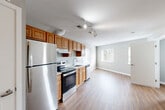 Located at 7127 Chestnut St NW in Washington, DC, this one-bedroom, one-bathroom unit offers a functional and well-appointed layout across a single floor. The open-concept main living area seamlessly connects the kitchen, dining, and living spaces, creating a cohesive and efficient use of space. The kitchen is outfitted with warm-toned wood cabinetry, stainless steel appliances including a refrigerator, electric range, and dishwasher, complemented by a double sink and white countertops. Track lighting overhead adds a modern touch and brightens the entire open area. Consistent hardwood-style flooring runs throughout the unit, adding warmth and visual continuity from room to room. A dedicated entrance leads into a hallway that provides access to the bedroom and bathroom, with four closets offering generous storage options. The bedroom features neutral gray walls, a window with outdoor views bringing in natural light, and its own closet. The overall aesthetic is clean and contemporary, with a neutral color palette of soft grays and whites that creates a calm, move-in-ready ambiance. This unit combines practical storage solutions with an open, airy layout suited for comfortable urban living in the Shepherd Park neighborhood of Northwest Washington, DC.