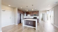 This single-floor residence offers a thoughtfully designed layout that balances modern style with everyday functionality. At its heart is a well-equipped kitchen featuring rich dark wood cabinetry, white quartz countertops, a full suite of stainless steel appliances including a refrigerator, electric range, built-in microwave, and dishwasher, all complemented by a classic subway tile backsplash. A central kitchen island provides additional counter space and serves as a natural gathering point. Light wood-style flooring flows throughout the main living areas, enhancing the bright, airy atmosphere.

The living area is generously sized, bathed in natural light through wide windows fitted with blinds that frame treetop views. A ceiling fan adds comfort to the space. The bedroom offers plush carpeting underfoot, a ceiling fan, and access to a walk-in closet, providing ample storage. The bathroom is finished with a stylish vanity featuring quartz countertops, modern brushed nickel fixtures, a large mirror, and wood-look flooring. A sliding glass door leads to a private balcony, offering a pleasant outdoor retreat with views of the surrounding greenery. The overall aesthetic is clean, contemporary, and move-in ready.