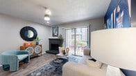 This 2-bedroom, 1-bathroom residence is thoughtfully arranged across a single floor, making efficient use of its compact footprint. The open-concept living and dining area serves as the heart of the home, anchored by a striking dark brick fireplace and a sliding glass door that provides direct outdoor access and fills the space with natural light. A bold navy accent wall adds a contemporary design element, complemented by wood-style flooring throughout the main living areas.

The kitchen is well-appointed with stainless steel appliances, including a range, microwave, dishwasher, and refrigerator. Grey cabinetry, marble-style countertops, and a classic white subway tile backsplash give the kitchen a clean, modern aesthetic. Wood-look flooring continues here, adding cohesion to the space.

The primary bedroom features plush carpeting, a ceiling fan, and a recessed window nook with a navy blue accent, offering a cozy reading or lounging area. The second bedroom maintains a similar layout with natural light from a window. The bathroom includes a shower-tub combination, a single-sink vanity with marble-style countertops, grey cabinetry, and a large framed mirror. A textured ceiling is consistent throughout the residence.