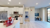Located at 4500 E 3rd St in Bloomington, Indiana, this well-appointed one-bedroom, one-bathroom unit offers a thoughtfully designed open-concept layout across a single floor. Light wood-tone flooring flows throughout, tying together each space with a clean, contemporary aesthetic.

The kitchen is a standout feature, showcasing crisp white shaker cabinetry, a stylish patterned tile backsplash, and a full suite of stainless steel appliances including a side-by-side refrigerator, electric range, over-the-range microwave, and dishwasher. A central island with an undermount sink and pendant lighting above provides additional workspace and casual seating.

The living room is bright and open, benefiting from large windows and a glass door that lead directly to a private balcony with outdoor views. Recessed lighting complements the natural light throughout.

The bedroom is a comfortable, well-sized retreat featuring a ceiling fan, a large window with a roller shade offering outdoor views, and light flooring consistent with the rest of the unit.

The bathroom is finished with a white vanity, quartz countertop, undermount sink, and a glass-enclosed shower. A dedicated laundry room houses a full-size side-by-side washer and dryer with built-in shelving above, adding exceptional functional convenience to this modern unit.