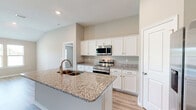 Located at 235 Treadstone Way in Fairhope, Alabama, this single-story home offers a thoughtfully designed layout with 3 bedrooms, 3 bathrooms, and a dedicated garage. The open-concept kitchen and living area serves as the heart of the home, featuring granite countertops, a central island with a double-basin sink, crisp white cabinetry, and stainless steel appliances including a range, microwave, and refrigerator. Light wood-tone luxury vinyl plank flooring flows throughout, adding warmth and continuity to the space. The living area is bright and airy, with neutral walls that complement the clean, modern aesthetic. The primary bedroom includes a tray ceiling with a ceiling fan and large windows that invite natural light and outdoor views. A spacious walk-in closet with wire shelving provides generous storage. The three bathrooms are finished consistently with granite vanity tops and white cabinetry. A dedicated laundry room houses a full-size washer and dryer. The attached garage is well-lit and offers ample space for vehicles and storage. Throughout the home, recessed lighting, tall ceilings, and a neutral color palette create a cohesive and comfortable living environment.