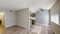 Located at 15328 Albers St in the Van Nuys neighborhood of Los Angeles, this single-floor unit offers a clean, functional layout with modern finishes throughout. The entry area welcomes residents with light wood-look laminate flooring and a large window fitted with vertical blinds, allowing natural light to filter into the open living space. The living area is generously proportioned, featuring the same wood-look flooring, neutral warm-gray walls, white baseboards, and a ceiling fan overhead that adds both style and practical comfort. A textured ceiling is consistent throughout the main living areas. The kitchen is accessible via a pass-through opening and is equipped with dark gray cabinetry, light countertops, a stainless steel sink, a gas range, and a stainless steel refrigerator, providing ample storage and counter space. The bedroom is carpeted with plush gray-toned carpet, accented by a bold slate-blue feature wall and a window with vertical blinds that brings in natural light. The bathroom is well-appointed with a wide vanity mirror, a single-basin sink set in a quartz-style countertop, a toilet, and a sliding-door shower enclosure. Overall, the unit presents a cohesive, updated aesthetic with practical amenities throughout.