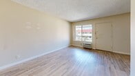 Located at 11811 Pioneer Blvd in Norwalk, California, this single-floor, one-bedroom, one-bathroom unit offers a practical and efficiently arranged layout. Light wood-style flooring runs throughout the unit, creating a consistent and clean aesthetic across all rooms.

The living room serves as the main gathering area, featuring neutral beige walls, a textured ceiling, and a large sliding window that allows natural light to fill the space. A wall-unit air conditioner and a front entry door are also situated in this room, providing direct access to the exterior.

The galley-style kitchen is positioned adjacent to the living area and features dual-basin countertop sinks, ample upper and lower cabinetry in a light finish, a gas range, and additional counter space along the opposite wall. The efficient corridor layout maximizes functionality within a compact footprint.

The bedroom is a well-proportioned private retreat with a large window fitted with vertical blinds that allow natural light while maintaining privacy. A sliding-door closet provides dedicated storage, and the room's neutral tones contribute to a calm atmosphere.

The full bathroom includes a single-sink vanity with a white cabinet base, a large mirror, and a shower-tub combination enclosed by sliding glass doors, offering a clean and functional design.