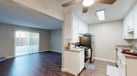 This single-floor residence in Castro Valley, California offers a thoughtfully designed layout that balances functionality and comfort. The kitchen is a standout feature, equipped with stainless steel appliances including a refrigerator, range, and dishwasher, complemented by white cabinetry, gray countertops, and wood-look flooring. A skylight overhead floods the space with natural light, while a ceiling fan adds practical comfort. The kitchen opens seamlessly into the living area through an arched passage, where sliding glass doors with vertical blinds provide outdoor views and abundant natural light. The living area continues the wood-look flooring, creating a cohesive aesthetic throughout the common spaces. The bedrooms are carpeted for warmth and comfort, each featuring ceiling fans and generous closet space. One bedroom includes a spacious walk-in closet with dual hanging rods and shelving. The two bathrooms are finished with tile surrounds, white vanity cabinetry, and gray countertops — one offering a tub-shower combination, the other a standalone shower with a glass enclosure. Clean neutral tones and consistent finishes throughout create a cohesive, move-in-ready atmosphere.