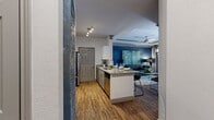 This thoughtfully designed 2-bedroom, 1-bathroom residence offers a cohesive open-concept layout that seamlessly connects the kitchen, dining, and living areas. The kitchen is a standout feature, showcasing granite countertops, white cabinetry, a subway tile backsplash, stainless steel appliances including a refrigerator, range, and built-in microwave, and a large peninsula with bar seating — ideal for both everyday meals and casual entertaining. Wood-style plank flooring runs throughout the main living spaces, adding warmth and continuity.

The living room is anchored by a bold navy accent wall, a tray ceiling with crown molding, a ceiling fan, and large windows with patio door access that invite ample natural light. A hallway connects the bedrooms and bathroom, with the primary bedroom offering carpeted flooring, a window with natural light, and a dedicated closet. The second bedroom provides versatile space for various needs.

The bathroom features granite countertops, grey cabinetry, wood-style flooring, and a shower-tub combination. A dedicated closet adds practical storage to round out the functional layout of this well-finished single-level residence.
