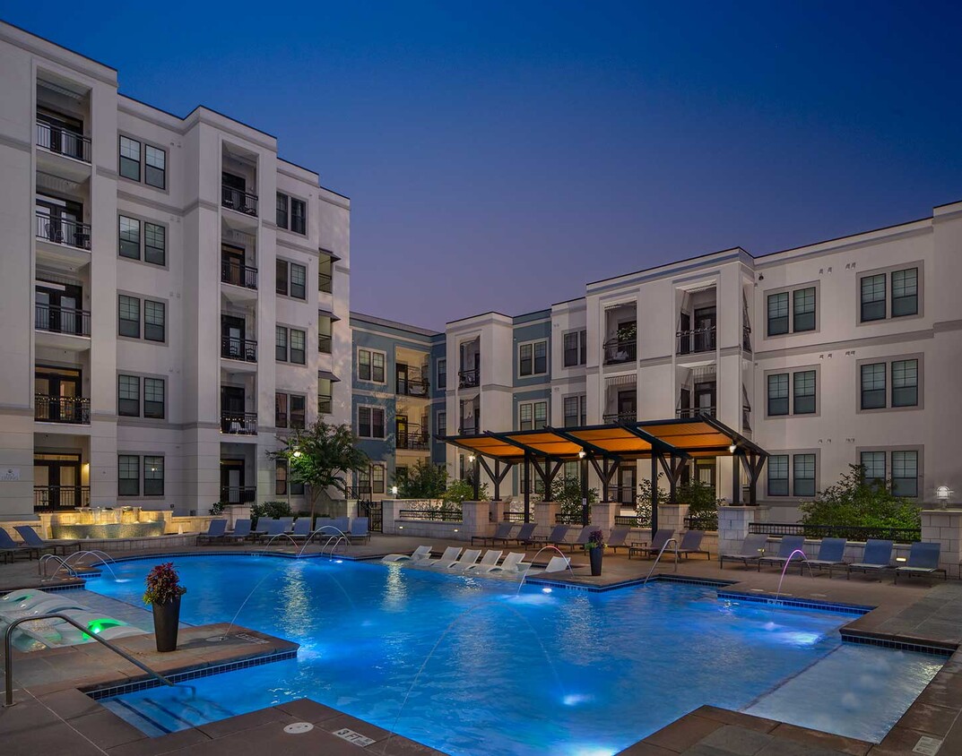 Toma al atardecer de la piscina con asientos tipo lounge dentro del agua, sillas lounge adicionales, fuente iluminada y área cubierta - Elle of Buckhead