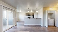 Located at 6185 E Medalist Ln in Nampa, Idaho, this single-floor unit offers a thoughtfully designed layout with modern finishes throughout. The open-concept living and kitchen area serves as the heart of the home, featuring durable wood-look flooring, neutral-toned walls, and a kitchen island with dark countertops and pendant lighting overhead. The kitchen is equipped with black appliances, including a refrigerator, electric range, and microwave, complemented by warm wood-grain cabinetry, a white subway tile backsplash, and a walk-in pantry for added storage.

The bedrooms are carpeted and filled with natural light from sliding or standard windows, offering views of the surrounding neighborhood. One bedroom features a closet with built-in shelving. The bathrooms are finished with wood-look flooring, wood-grain vanity cabinetry, and subway tile accents, providing a clean and cohesive aesthetic. A dedicated laundry area houses a full-size washer and dryer with overhead shelving for convenience.

Throughout the unit, textured ceilings, white trim, and a consistent neutral palette create a calm, move-in-ready atmosphere. Sliding door access adds connectivity between interior living spaces.