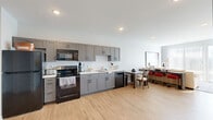 Located at 229 S Grant St in Bloomington, Indiana, this well-appointed 2-bedroom, 2-bathroom residence offers a thoughtfully designed single-floor layout. The open-concept living area seamlessly integrates the kitchen, dining, and living spaces, creating a bright and functional environment. Light wood-style flooring flows throughout the main living areas, enhancing the clean, contemporary aesthetic.

The kitchen is outfitted with grey shaker-style cabinetry, light countertops, and black stainless steel appliances, including a refrigerator, range, microwave, and dishwasher. Large windows in the living room allow generous natural light to fill the space, with a wall-mounted TV and access to outdoor views completing the area.

Both bedrooms feature plush carpeting and closet storage. The primary bedroom benefits from bright windows with views of the surrounding area. Each bathroom is finished with grey vanity cabinetry, white countertops, and tiled flooring, with one bathroom featuring a full tub-shower combination. Additional conveniences include in-unit laundry and multiple closets for ample storage throughout. The overall ambiance is modern, clean, and move-in ready.