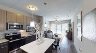 This thoughtfully designed one-bedroom, one-bathroom residence offers a comfortable and modern living experience across a single floor. The open-concept layout seamlessly connects the kitchen, dining, and living areas, creating a cohesive and functional space throughout.

The kitchen is a standout feature, outfitted with stainless steel appliances including a refrigerator, range, microwave, and dishwasher. Two-toned cabinetry pairs light upper cabinets with dark lower units, complemented by a light quartz countertop and a central island that doubles as a breakfast bar. Pendant lighting above the island adds a stylish touch, while hardwood-style flooring extends throughout the main living areas.

The living room is bright and inviting, benefiting from natural light through large windows and a sliding glass door that opens to an outdoor space. A ceiling fan enhances comfort in both the living room and bedroom.

The bedroom is a calm retreat, featuring windows with exterior views, hardwood-style flooring, and ample space for furnishings. The full bathroom includes a tub/shower combination, tile flooring, a vanity with dark cabinetry, and a wall-mounted storage cabinet, providing practical functionality throughout.