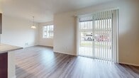 Located at 2715 62nd Ave E, Unit D14 in Fife, WA, this single-floor, 3-bedroom, 2-bathroom apartment offers 950 square feet of well-organized living space. The open-concept kitchen and living area serves as the heart of the unit, featuring rich dark-cherry cabinetry, granite-style countertops, a peninsula with a built-in sink, stainless steel refrigerator, and black appliances including a range and microwave. Track lighting illuminates the kitchen, while light wood-style vinyl flooring runs consistently throughout the entire unit, creating a cohesive and clean aesthetic. The living room benefits from a large sliding glass door with vertical blinds, flooding the space with natural light and providing outdoor views. The primary bedroom spans 160 square feet, offering ample space. Additional bedrooms are bright and airy, each featuring windows with blinds and neutral wall tones. Both bathrooms are equipped with tub-shower combinations featuring floor-to-ceiling speckled stone-style surround walls and granite-topped vanities. Two hallways connect the rooms efficiently across the single-floor layout. The unit's light, neutral color palette and consistent finishes throughout contribute to a clean, modern, and move-in-ready ambiance.