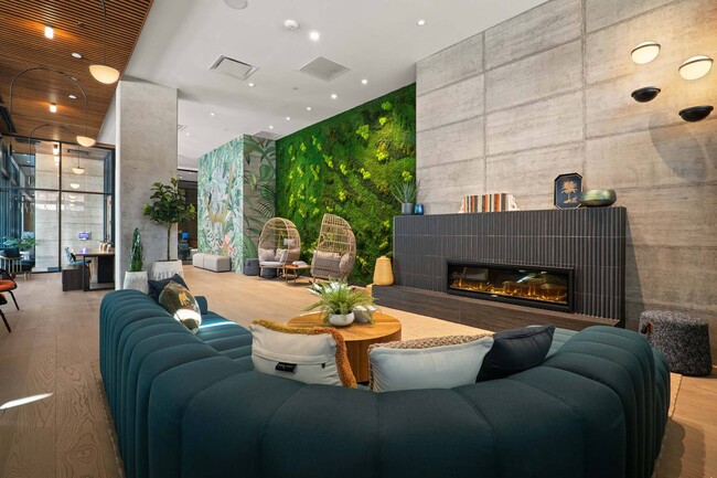 Ingrese a un salón moderno con chimenea, un cómodo sofá y una llamativa pared verde. - Windsor 3000 Huron