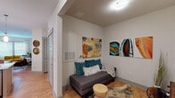 Located at 60 Mills Gap Rd in Asheville, NC, this well-appointed single-floor residence offers a thoughtfully designed layout with contemporary finishes throughout. The open-concept kitchen serves as a central hub, featuring a quartz waterfall island with an undermount sink, stainless steel appliances, gray shaker-style cabinetry with glass accents, subway tile backsplash, and pendant lighting over warm hardwood flooring. The living area is bright and welcoming, with large windows that invite natural light, a ceiling fan, direct outdoor access via a exterior door, and hardwood floors that extend throughout the common areas. A cozy sitting nook with additional wall space provides a versatile secondary lounge area. The primary bedroom offers plush carpeting, a ceiling fan, and a walk-in closet, while a second bedroom enjoys views of the outdoors through large windows and mid-century modern décor accents. Both bathrooms are finished with stone-look tile flooring, white vanities with clean countertops, and full tub-shower combinations. Throughout the residence, neutral wall tones create a calm, cohesive backdrop that complements the eclectic, art-forward styling visible in each room.