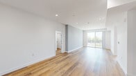 Located at 8940 Reseda Boulevard in Northridge, CA, this thoughtfully designed 2-bedroom, 2-bathroom residence offers a clean, modern aesthetic throughout its single-floor layout. Warm wood-look flooring flows seamlessly across every room, complemented by crisp white walls, recessed lighting, and a light, neutral color palette that creates an inviting, contemporary atmosphere.

The open-concept living and kitchen area serves as the heart of the home. The kitchen is outfitted with sleek, flat-front charcoal gray cabinetry extending to the ceiling, white quartz countertops, stainless steel appliances including a gas range, microwave, and refrigerator, and an undermount sink. The living area is bright and airy, with a sliding glass door that opens to an outdoor balcony, filling the space with natural light and providing outdoor views.

The spacious primary bedroom features recessed lighting and its own sliding glass door with balcony access. The second bedroom is well-proportioned with a large window allowing generous natural light. Both rooms are served by a walk-in closet with built-in shelving and hanging rods for ample storage.

The two bathrooms are finished in a clean, modern style. One features a glass-enclosed tub and shower combination with tiled surround, while the second offers a charcoal vanity with white countertop and a backlit mirror. A connecting hallway ties all spaces together efficiently.