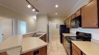 Located at 100 Estella Ct in Florence, Alabama, this single-story residence offers a well-organized layout with functional living spaces throughout. The kitchen is designed in a galley style, featuring warm wood cabinetry, light countertops, a double-basin sink, and black appliances including a refrigerator, range, and built-in microwave. Track lighting and recessed fixtures illuminate the space, which connects seamlessly to the open living and dining area. The living area is finished with rich hardwood-style flooring, crown molding, a pendant light fixture, and a ceiling fan, creating a comfortable and cohesive atmosphere. Multiple bedrooms carry the same hardwood-style flooring and are each equipped with ceiling fans and windows fitted with horizontal blinds that allow for natural light and outdoor views. The bathrooms are finished with tile flooring, wood vanity cabinetry, light countertops, large mirrors, and tub-shower combinations with brushed nickel fixtures. A dedicated laundry area includes wire shelving, a dryer vent connection, and an accessible electrical panel. Neutral wall tones throughout the home contribute to a clean, versatile aesthetic suitable for a variety of furnishing styles.
