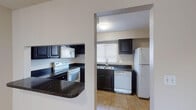 Located at 7903 Sunshine Palm Way in Tampa, Florida, this two-story home offers a practical and well-organized layout across both levels. The kitchen is a standout feature, equipped with dark cabinetry contrasted by dark granite-style countertops, white appliances including a range, built-in microwave, dishwasher, and refrigerator, and tile flooring that adds durability and easy maintenance. A pass-through window connects the kitchen to the adjacent living area, enhancing the open feel of the space. The living areas are finished with warm, neutral-toned carpeting and feature sliding glass doors that invite natural light and provide outdoor access. The bedrooms are generously sized, also carpeted, and include well-designed closets — one featuring a spacious walk-in with built-in shelving and hanging rods on both sides for ample storage. The primary bathroom area includes a dark-cabinetry vanity with a granite-style countertop and tile flooring, consistent with the home's overall design palette. The lower level includes a dedicated utility room tucked beneath the staircase, housing the water heater and washer/dryer hookups with tile flooring and wire shelving. Textured ceilings are present throughout, and the staircase connects both floors with a clean, neutral aesthetic.