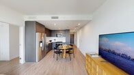 Located along Miami's vibrant Biscayne Boulevard in the sought-after Edgewater neighborhood, this thoughtfully designed 2-bedroom, 2-bathroom residence offers a clean, contemporary aesthetic throughout. Light wood-tone flooring flows seamlessly across the open-plan living area, connecting the living room to a modern kitchen outfitted with dark wood cabinetry, stainless steel appliances, and a crisp white backsplash. A dedicated dining space comfortably accommodates a round table, making the layout ideal for everyday living and entertaining.

A bright, art-lined hallway guides residents to both bedrooms. The primary bedroom features floor-to-ceiling windows that frame sweeping views of the Miami skyline and cityscape, filling the room with natural light. The second bedroom is equally serene, with soft neutral tones and warm wood accents. Both rooms include closet storage, and three closets are available throughout the unit.

The two bathrooms are finished in a clean, minimalist style — one featuring a dark-cabinetry vanity with a large mirror and city views, the other with a full soaking tub and shower combination with white tile surround. Recessed lighting and white walls throughout maintain a bright, airy atmosphere that complements Miami's sun-filled lifestyle.