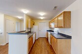 Located at 1530 Blackbird Lane in Howell, Michigan, this one-bedroom, one-bathroom home offers a well-designed layout that makes efficient use of its space throughout. Hardwood-style flooring flows consistently across the main living areas, lending a warm and cohesive feel to the interior.

The galley-style kitchen is a standout feature, lined with warm wood cabinetry and dark countertops on both sides, and equipped with a white range, dishwasher, and refrigerator. A peninsula with additional counter space connects the kitchen to the dining area, creating an open, functional flow for everyday living.

The living area is bright and open, benefiting from large windows dressed with horizontal blinds that allow natural light to fill the room. The bedroom mirrors this brightness with its own generous window offering neighborhood views, and includes a double-door closet providing ample storage. Additional closet space is available throughout the unit.

The bathroom features a wood-toned vanity with a dark countertop and a large mirror, maintaining the consistent design language of the home. A dedicated laundry room with side-by-side washer and dryer hookups adds a practical convenience. Carpeted stairs lead to access points within the building, completing this thoughtfully arranged home.