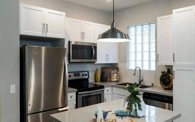 Cocina moderna con electrodomésticos de acero inoxidable y gabinetes blancos. - Amerige Pointe