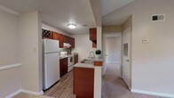 Located at 111 Edie Ann Dr in Lafayette, Louisiana, this single-story residence offers a well-designed, open-concept layout that connects the kitchen and living areas seamlessly. The kitchen is a standout feature, showcasing rich cherry wood cabinetry — including a distinctive wine rack — granite-style countertops, a double stainless steel sink with a modern faucet, wood-look flooring, a mosaic tile backsplash, and a full suite of white appliances including a refrigerator, range, and dishwasher. A peninsula counter provides an informal dining or prep area and visually connects the kitchen to the adjacent dining and living spaces. The living area benefits from vaulted ceilings and a ceiling fan, with a large window that allows natural light to fill the room. The bedrooms are carpeted for comfort, each equipped with a ceiling fan and ample natural light. The primary bedroom includes access to a walk-in closet and built-in shelving. The bathroom is finished with cherry wood cabinetry, granite-style countertops, wood-look tile flooring, and a tub-shower combination. Throughout the residence, neutral tones and consistent finishes create a cohesive and welcoming ambiance.