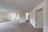 Located at 415 Deerfield Rd in East Syracuse, NY, this single-floor residence offers three bedrooms, two bathrooms, and a thoughtfully arranged layout that maximizes everyday functionality. The open living and dining areas are finished with wall-to-wall carpeting and neutral warm-toned walls, creating a clean, inviting atmosphere. A ceiling fan in the living area adds comfort, while sliding glass doors lead directly to a private balcony overlooking a landscaped courtyard with mature trees — a pleasant outdoor retreat. The kitchen features warm wood cabinetry, dark granite-style countertops, hardwood-style flooring, and black appliances including a dishwasher and range, with a window providing natural light and exterior views. Each of the three bedrooms is carpeted and finished in neutral tones, offering a calm and functional space. The bedrooms are well-served by a total of four closets, including sliding double-door closets that provide generous storage. The bathrooms are cleanly appointed, with one featuring a full tub-and-shower combination with classic white tile surround. Baseboard heating is present throughout, and the bedrooms include wall-mounted air conditioning units for year-round comfort. The overall design is practical and move-in ready.