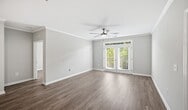 Located at 141 Park at N Hills St in Raleigh, NC, this 990-square-foot, single-story apartment (Design 2A #305) offers three bedrooms and two bathrooms with a well-designed, functional layout. The kitchen is a standout feature, equipped with white shaker-style cabinetry, granite countertops, a subway tile backsplash, stainless steel appliances including a refrigerator, dishwasher, microwave, and electric range, plus a central island and a built-in desk nook. Light tile flooring anchors the kitchen, which opens to the living area finished with wood-look hardwood-style flooring throughout. Crown molding adds a refined touch to the main living spaces and bedrooms. The primary bedroom measures 170 square feet and features ceiling fan, crown molding, and French doors leading to an outdoor area. Additional bedrooms also include ceiling fans and windows for natural light. The primary bathroom offers a glass-enclosed walk-in shower and white vanity, while the second bathroom features a full tub-shower combo. A dedicated in-unit laundry closet houses a stacked washer and dryer. Neutral gray-toned walls and clean white trim create a cohesive, modern aesthetic throughout the entire unit.