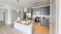 Located at 300 District Dr in Asheville, NC, this well-appointed 3-bedroom, 2-bathroom residence offers a thoughtfully designed single-floor layout. Light wood-style flooring flows seamlessly throughout, complementing the clean, neutral palette that defines the space.

The open-concept kitchen and living area serves as the heart of the home, featuring gray shaker cabinetry, granite countertops, a large central island with a built-in sink, stainless steel appliances, subway tile backsplash, and pendant lighting — all accented by track lighting overhead. A pantry provides additional storage convenience.

Each of the three bedrooms offers natural light through large windows with views of the surrounding neighborhood, and ceiling fans for year-round comfort. The generously sized primary bedroom includes a walk-in closet outfitted with wire shelving systems. Additional closets are plentiful throughout the unit, totaling five in all.

The two bathrooms mirror the kitchen's refined aesthetic, featuring gray shaker vanities, granite countertops, large framed mirrors, and dark tile-surround tub/shower combinations. A sliding glass door in one area of the residence provides outdoor access, adding to the bright, airy feel of this well-organized and modern home.