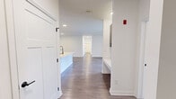 This single-story home in Whitestown, Indiana offers a thoughtfully designed layout with four bedrooms, two full bathrooms, a dedicated laundry room, and an open-concept kitchen and living area. The interior showcases a clean, modern aesthetic defined by crisp white walls, wood-look plank flooring in the main living areas, and dark-toned cabinetry with black hardware accents throughout.

The kitchen serves as a central hub, featuring a shiplap-accented island with a white quartz countertop and undermount sink, stainless steel appliances including a refrigerator, range, and microwave, and dark wood cabinetry extending to the ceiling. Recessed lighting illuminates the open living and kitchen space, which flows seamlessly toward the hallway and bedrooms.

The bedrooms are carpeted for comfort, with several rooms featuring ceiling fans and windows that bring in natural light and neighborhood views. The hallway connecting the bedrooms is finished with plush carpet and panel-style doors with black hardware.

The two bathrooms offer wood-look flooring, dark wood vanities with white countertops, and black fixtures. One bathroom features a tub-shower combination, while the other includes a glass-enclosed shower with large-format marble-look tile. The laundry room includes side-by-side washer and dryer units beneath dark upper cabinetry for additional storage.