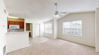 Located at 1700 Eagle Landing Blvd in Hanahan, South Carolina, this two-bedroom, two-bathroom home offers a well-designed single-floor layout with a bright and open feel throughout. The living area features vaulted ceilings with a ceiling fan, soft carpet flooring, and multiple windows that fill the space with natural light. A textured ceiling adds a classic touch to the main living space, which flows seamlessly toward the entryway and kitchen. The galley-style kitchen is equipped with warm wood cabinetry, granite-style countertops, white appliances including a refrigerator and range, and wood-look flooring that contrasts nicely with the carpeted areas. A peninsula counter provides additional workspace and separation from the living area. Both bedrooms are carpeted and feature ceiling fans and natural light from windows. The primary bedroom is generously sized and includes a walk-in closet outfitted with wire shelving and organizational storage. The second bedroom also offers ample closet space with double bifold doors. Both bathrooms are identically appointed with wood-toned vanities, granite-style countertops, tub-shower combinations with white tile surrounds, large mirrors, and wood-look flooring. Three total closets throughout the home provide excellent storage capacity for everyday living.