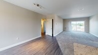 Located at 7 West St in Walpole, Massachusetts, this single-floor residence offers a thoughtfully designed layout with modern finishes throughout. The open-concept living and kitchen area serves as the heart of the home, where rich hardwood-style flooring transitions seamlessly into plush carpeting in the living space. The kitchen is equipped with stainless steel appliances, including a refrigerator, range, and microwave, complemented by dark wood cabinetry and granite countertops. A breakfast bar peninsula adds both functionality and style. Natural light flows in through generously sized windows, offering views of the surrounding neighborhood. The bedrooms feature wall-to-wall carpeting and ample windows that bring in abundant daylight. The primary bedroom includes access to a dedicated bathroom outfitted with a dark wood vanity, granite countertop, a large mirror, and tile flooring. A secondary bathroom provides a full soaking tub and shower combination with chrome fixtures and tile floors. A dedicated in-unit laundry area houses a full-sized washer and dryer. Neutral-toned walls and clean white trim throughout create a bright, cohesive aesthetic. The floorplan model reveals a spacious and efficient layout well-suited for comfortable everyday living.