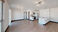 Located at 11036 Moorpark St in the North Hollywood neighborhood of Los Angeles, this modern single-floor unit showcases a clean, contemporary design throughout. The open-concept living and kitchen area is bright and airy, anchored by smooth hardwood-style flooring and crisp white walls that create a fresh, minimalist aesthetic.

The kitchen is a standout feature, equipped with sleek white cabinetry extending to the ceiling, a full suite of stainless steel appliances including a gas range, built-in microwave, and a French door refrigerator. A generous peninsula with a light quartz countertop and an undermount double sink provides ample prep space and separates the kitchen from the living area. Pendant lighting above the peninsula adds a refined touch.

The living area is generously proportioned, filled with natural light streaming through expansive floor-to-ceiling windows and sliding glass doors that open to a private balcony, offering open views of the surrounding Los Angeles neighborhood. Track lighting provides additional illumination throughout.

The bathroom is finished in a clean, modern style with large-format tile in the shower/tub combination, chrome fixtures, and a tub with an overhead rain-style showerhead. The overall design of the space prioritizes functionality and contemporary style, making it a well-appointed urban residence.