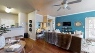 This 2-bedroom, 1-bathroom single-floor residence offers a thoughtfully designed layout that maximizes every square foot. The open-concept living and kitchen area serves as the heart of the home, where warm hardwood flooring flows throughout. The living room stands out with a bold teal accent wall, crown molding, a ceiling fan, and built-in display shelving — creating a vibrant yet inviting atmosphere. The kitchen is well-equipped with stainless steel appliances, including a range, dishwasher, and over-the-range microwave, complemented by granite countertops, a tile backsplash, and ample white cabinetry. The primary bedroom features plush carpeting, a ceiling fan, and a striking teal accent wall with stylish sconce lighting. The second bedroom also offers carpeted flooring and a ceiling fan, providing a cozy and functional space. The shared bathroom includes a vanity with granite countertops, white cabinetry, a full tub-shower combination with classic white tile surround, and hardwood flooring. A dedicated closet with shelving and hanging space completes the unit, adding practical storage. Crown molding and ceiling fans are consistent throughout, lending a cohesive and polished character to the entire residence.