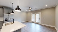 Located at 2121 Langhorne Rd in Lynchburg, Virginia, this thoughtfully designed 2-bedroom, 1-bathroom unit offers a comfortable and modern living experience across a single floor. The open-concept layout seamlessly connects the kitchen and living area, creating an efficient and welcoming flow. The kitchen is a standout feature, showcasing gray shaker-style cabinetry, white quartz countertops, a subway tile backsplash, stainless steel appliances, and a central island with pendant lighting — ideal for both everyday cooking and entertaining. The living area extends naturally from the kitchen, featuring light hardwood-style flooring, crown molding, a ceiling fan, and French doors that invite natural light and outdoor access. Both bedrooms are carpeted for comfort and include ceiling fans. The spacious primary bedroom offers generous square footage and connects to a hallway with a dedicated closet. The full bathroom is cleanly finished with gray cabinetry, a white quartz vanity, tub-shower combination, and coordinating light fixtures. Neutral warm-gray tones throughout the space create a cohesive, contemporary aesthetic that is move-in ready.