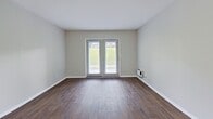 This 550 square foot apartment offers a thoughtful layout that maximizes space and functionality. The single-floor design includes one bedroom, measuring 140 square feet, and two full bathrooms, providing convenience and privacy. The heart of the home is a combined kitchen and living room area, creating an open and inviting atmosphere.

The kitchen boasts modern white cabinetry, complemented by sleek black appliances including a refrigerator and dishwasher. Granite countertops add a touch of elegance, while a window above the sink allows natural light to brighten the space. The living area features durable wood-look flooring, creating a warm and inviting ambiance. Large windows in both the living room and bedroom flood the space with natural light and offer views of the surrounding greenery.

The bedroom is carpeted for comfort and includes a sizable window, enhancing the sense of space. Both bathrooms are efficiently designed, with one featuring a bathtub-shower combination and white tile surround. The apartment's neutral color palette, predominantly in soft whites and beiges, creates a clean, modern aesthetic that allows for personal decorating touches.

Despite its compact size, the apartment doesn't compromise on amenities. It includes modern fixtures, ample storage solutions, and a thoughtful layout that separates private and communal spaces effectively. This apartment is ideal for those seeking a low-maintenance, high-function living space in an urban setting.
