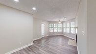 Located at 4155 Satellite Blvd in Duluth, Georgia, this single-floor residence offers a thoughtfully laid-out interior with a neutral color palette and a clean, updated aesthetic throughout. The open living and dining area is a standout feature, showcasing durable wood-look plank flooring, recessed lighting, a ceiling fan, and a textured ceiling. A bay-style window arrangement floods the space with natural light while offering views of the surrounding greenery, creating a bright and welcoming atmosphere. A glass-paneled door provides additional outdoor access from the main living area. The kitchen is well-appointed with white shaker-style cabinetry, granite-look countertops, a subway tile backsplash, and stainless steel appliances including a refrigerator and electric range with an overhead vent. Wood-look flooring continues seamlessly through the kitchen. The bedrooms feature plush carpeting, ample closet space with built-in shelving, and windows that invite natural light. The bathroom is outfitted with a white vanity, granite-look countertop, a large mirror with overhead lighting, wood-look flooring, and a tiled tub and shower combination. Overall, the space presents a functional and comfortable layout with consistent, modern finishes throughout.