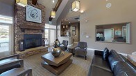 Located at 7298 Banberry Dr in Widefield, Colorado, this single-story community clubhouse offers a thoughtfully designed gathering space with a range of amenities to serve its residents. The centerpiece of the facility is a spacious main lounge boasting soaring vaulted ceilings with exposed wood beams, elegant lantern-style pendant lighting, and a dramatic floor-to-ceiling stacked stone fireplace. Rustic barn-style sliding doors, rich hardwood-look flooring, and curated artwork contribute to the warm, contemporary aesthetic throughout.

The business center is bright and functional, featuring a long granite-topped workstation with multiple computers, pendant lighting, and ample natural light from large windows. A dedicated conference room provides a more intimate setting with a round table, tray ceiling, and views overlooking the outdoor area.

A cozy media lounge offers a full stacked stone accent wall with a mounted flat-screen television and built-in speakers, ideal for group viewing. A well-equipped galley kitchen includes granite countertops, stainless steel appliances, rich cabinetry with mosaic tile accents, and wood-look tile flooring. Additional seating areas with accent chairs and thoughtful décor complete this versatile and welcoming community space.