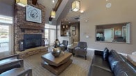 Located at 7298 Banberry Dr in Widefield, Colorado, this single-story community clubhouse offers a thoughtfully designed gathering space with a range of amenities to serve its residents. The centerpiece of the facility is a spacious main lounge boasting soaring vaulted ceilings with exposed wood beams, elegant lantern-style pendant lighting, and a dramatic floor-to-ceiling stacked stone fireplace. Rustic barn-style sliding doors, rich hardwood-look flooring, and curated artwork contribute to the warm, contemporary aesthetic throughout.

The business center is bright and functional, featuring a long granite-topped workstation with multiple computers, pendant lighting, and ample natural light from large windows. A dedicated conference room provides a more intimate setting with a round table, tray ceiling, and views overlooking the outdoor area.

A cozy media lounge offers a full stacked stone accent wall with a mounted flat-screen television and built-in speakers, ideal for group viewing. A well-equipped galley kitchen includes granite countertops, stainless steel appliances, rich cabinetry with mosaic tile accents, and wood-look tile flooring. Additional seating areas with accent chairs and thoughtful décor complete this versatile and welcoming community space.