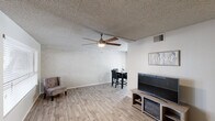 This single-floor residence offers a practical and comfortable layout across two bedrooms and two bathrooms. The open living and dining area forms the heart of the unit, featuring light wood-look flooring, textured walls, and a textured ceiling throughout. A large ceiling fan with an integrated light fixture anchors the living space, which flows naturally into the dining area — illuminated by a sliding glass door that provides natural light and direct access to an outdoor patio.

The galley-style kitchen is efficiently designed with white cabinetry, white subway tile backsplash, grey countertops, and a full suite of stainless steel appliances, including a range, microwave, refrigerator, and dishwasher. A hallway connects the kitchen to both bathrooms and bedrooms, offering a logical flow through the unit.

The primary bedroom is a comfortable size, equipped with a ceiling fan and a window with blinds allowing natural light. The second bedroom is similarly appointed with a window and light flooring. Both bathrooms feature updated vanities with clean, modern finishes. A dedicated closet provides additional storage, completing this efficiently organized single-level home.