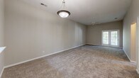 This single-floor, 3-bedroom, 2-bathroom home at 511 Bethabara Hills Court in Winston-Salem, NC offers a practical and comfortable layout. The interior is finished with neutral-toned carpet throughout the living and bedroom areas, complemented by light beige walls that create a clean, cohesive aesthetic.

The spacious primary bedroom is notably generous in size, featuring vaulted ceilings, a ceiling fan, and a pendant light fixture, giving the room an open and airy feel. Multiple doors within the primary suite provide access to closets and connecting areas. Two additional bedrooms are well-sized, each equipped with ceiling fans and textured ceilings, with arched accent windows that allow natural light to filter in.

The two bathrooms are functional and straightforward. One bathroom includes a full tub-shower combo with a chrome curtain rod, while the other features a vanity with a warm-toned countertop, white cabinetry, and a well-lit mirror with globe lighting above. Both bathrooms include hard-surface flooring.

The floor plan also includes a kitchen area visible in the dollhouse view, along with a connected hallway and two closets for ample storage. The overall design prioritizes functionality with a neutral, move-in-ready palette throughout.