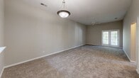 This single-floor, 3-bedroom, 2-bathroom home at 511 Bethabara Hills Court in Winston-Salem, NC offers a practical and comfortable layout. The interior is finished with neutral-toned carpet throughout the living and bedroom areas, complemented by light beige walls that create a clean, cohesive aesthetic.

The spacious primary bedroom is notably generous in size, featuring vaulted ceilings, a ceiling fan, and a pendant light fixture, giving the room an open and airy feel. Multiple doors within the primary suite provide access to closets and connecting areas. Two additional bedrooms are well-sized, each equipped with ceiling fans and textured ceilings, with arched accent windows that allow natural light to filter in.

The two bathrooms are functional and straightforward. One bathroom includes a full tub-shower combo with a chrome curtain rod, while the other features a vanity with a warm-toned countertop, white cabinetry, and a well-lit mirror with globe lighting above. Both bathrooms include hard-surface flooring.

The floor plan also includes a kitchen area visible in the dollhouse view, along with a connected hallway and two closets for ample storage. The overall design prioritizes functionality with a neutral, move-in-ready palette throughout.
