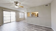 This single-story residence offers a thoughtfully designed layout with a cohesive neutral color palette throughout. The open living and dining area is a standout feature, finished with light wood-look flooring and ceiling fans that provide both style and function. Textured ceilings add subtle architectural character to the space. A pass-through window connects the living area to the kitchen, enhancing the open feel while maintaining defined zones. The kitchen is equipped with stainless steel appliances, including a refrigerator, electric range, and over-the-range microwave, complemented by white shaker-style cabinetry, light quartz countertops, and a classic white subway tile backsplash. Sliding glass doors in the living area allow an abundance of natural light and provide access to an outdoor space. The bedroom features plush wall-to-wall carpeting, a ceiling fan, and a window with blinds for natural light and privacy. The bathroom is finished with wood-look tile flooring, a white vanity with brushed nickel hardware, and a tiled shower-tub combination, maintaining the clean, modern aesthetic found throughout the residence.