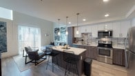 Located in the vibrant Arts District of Los Angeles, this two-story residence at 950 E Third St offers a well-appointed, modern living experience. The open-concept kitchen is a standout feature, showcasing two-tone cabinetry with white upper cabinets and wood-grain lower cabinets, a subway tile backsplash, stainless steel appliances, and a large center island with pendant lighting and bar seating — ideal for both cooking and casual dining. Light wood-tone flooring flows throughout the main living areas, contributing to a bright and cohesive aesthetic.

The bedrooms are generously sized, each equipped with ceiling fans for added comfort. One bedroom conveniently houses an in-unit stacked washer and dryer. A second-level loft-style bedroom provides additional flexible living space with neutral tones and natural light from a window above.

The bathrooms are clean and contemporary, featuring light tile flooring, wood-grain vanity cabinets, white quartz countertops, and walk-in glass-enclosed showers. Additional storage is provided by overhead cabinetry. Throughout the residence, recessed lighting and carefully selected finishes create a polished, urban atmosphere well-suited to the dynamic surroundings of downtown Los Angeles.