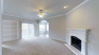 This well-appointed 2-bedroom, 2-bathroom single-floor residence offers a thoughtfully designed layout that balances comfort and style. The living area is a standout feature, showcasing plush carpeting, crown molding, and a classic white-mantled fireplace with tile surround — creating a warm and inviting focal point. A ceiling fan overhead enhances both the aesthetic and functionality of the space. An elegant arched passageway connects the living area to an adjacent room, adding architectural character and a sense of depth to the open floor plan. Large sliding glass doors with vertical blinds flood the living space with natural light while providing access to the outdoors. The neutral color palette throughout lends a clean, versatile backdrop suited to a variety of interior styles. The additional rooms continue the home's commitment to comfortable living, with generous proportions and consistent finishes. The combination of practical features and refined design details — from the crown molding to the arched entryways — gives this home a polished, cohesive feel throughout its single floor.