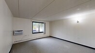 Located at 2815 Elisha Ave in Zion, IL, this single-floor, one-bedroom, one-bathroom unit offers a practical and straightforward layout across a compact but well-organized floor plan. The entrance leads into a central hallway adorned with a decorative wall sconce, connecting the key living areas with ease. The combined living and dining room is the largest area of the unit, featuring neutral carpet flooring, a wall-mounted air conditioning unit, baseboard heating, and a sliding window that brings in natural light and views of the surrounding greenery. The functional kitchen is outfitted with warm oak cabinetry — both upper and lower — a gas range with overhead ventilation, a full-size refrigerator, and a stainless steel sink with ample counter space. Tile flooring completes the kitchen area. The bedroom is a comfortable, well-proportioned room with carpet flooring, a large window, baseboard heating, and a built-in double-door closet, providing practical storage. The unit includes a total of four closets distributed throughout, offering notable storage capacity. The bathroom features a tiled tub-and-shower combination with a handheld showerhead, grab bars, and classic light-toned tile walls. The overall aesthetic is clean and neutral, providing a functional living environment.