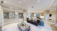 Located in Durham, NC, this sophisticated clubhouse offers a thoughtfully designed single-floor layout that combines upscale aesthetics with versatile amenities. The grand main lounge serves as the heart of the space, featuring large-format porcelain tile flooring, recessed lighting, and a striking curved decorative partition. Plush leather seating, textured stone accent walls, and floor-to-ceiling windows invite abundant natural light while offering views of the surrounding outdoor areas.

Adjacent to the lounge is a stylish bar and kitchen area, complete with a long white quartz island, bar stool seating, pendant lighting, and a full coffee station — ideal for social gatherings. A dedicated media lounge with a tray ceiling, mounted flat-screen TV, and upholstered armchairs provides a comfortable retreat.

The conference room features a solid wood table, upholstered seating, a wall-mounted display, and designer lighting, making it well-suited for professional meetings. A private business center with a workstation and large garden-view window rounds out the work-oriented spaces.

The fitness center, visible through expansive glass walls, is equipped with a variety of cardio and strength-training machines and benefits from ample natural light. Throughout, the clubhouse maintains a cohesive, contemporary design with neutral tones and refined finishes.