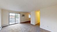 Located at 100 Ross Rd in Bridgeport, PA, this one-bedroom, one-bathroom residence offers a well-organized single-floor layout with a thoughtful mix of rooms including a living room, kitchen, bedroom, hallway, bathroom, and two closets. The carpeted living room is bright and open, featuring a wall-unit air conditioner, baseboard heating, and sliding glass doors that lead to a private balcony overlooking the community grounds and surrounding greenery. The entry area is defined by a classic wood-tone front door and a paneled accent wall, adding a touch of character to the space. The kitchen features light wood cabinetry, a full suite of black appliances including a range, dishwasher, and refrigerator, a double sink with a stone-look countertop, wood-look flooring, and a ceiling fan with light fixture. The generously sized bedroom is carpeted with ample natural light from a window with blinds, baseboard heating, and a set of louvered bifold closet doors providing convenient storage. The full bathroom presents clean white subway tile surround, a tub/shower combination, tile flooring, and a vanity with storage. The private balcony offers open views of the community, including landscaped grounds and a pool area visible in the distance.