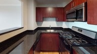 This 2-bedroom, 1-bathroom residence is thoughtfully designed with a clean, modern aesthetic throughout. Warm hardwood flooring flows seamlessly across the living areas and bedrooms, complemented by crisp white walls and bright flush-mount lighting. The open living area connects to a kitchen via a pass-through window, creating an airy, connected feel. The kitchen is well-equipped with rich dark wood cabinetry, dark granite countertops, a gas range, stainless steel microwave, and a deep undermount sink — offering both style and functionality. Both bedrooms are generously proportioned, featuring large windows that frame outdoor views of the surrounding neighborhood's tree canopy and rooftops, filling the rooms with natural light. One bedroom includes a closet with built-in shelving, providing practical storage. Baseboard heating runs along the perimeter of the rooms, ensuring year-round comfort. The bathroom features a full bathtub and shower combination with a curved curtain rod, a dark granite vanity countertop with an undermount sink, rich wood cabinetry, and clean white tile walls. The overall ambiance is bright, understated, and move-in ready, making it a versatile and comfortable living space.