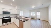 Located at 4001 E Jory St in Newberg, Oregon, this 2-bedroom, 2-bathroom unit offers a well-designed, single-floor layout with a clean, modern aesthetic throughout. Light wood-style flooring runs continuously across all rooms, creating a bright and cohesive feel.

The open-concept living area flows seamlessly from the kitchen, which features white shaker-style cabinetry, dark countertops, a subway tile backsplash, and a full suite of stainless steel appliances including a refrigerator, electric range, built-in microwave, and dishwasher. A peninsula with an integrated sink adds additional prep space and a natural division between the kitchen and the combined dining and living area. A sliding door provides access to a private balcony, while windows invite natural light into the living space.

The primary bedroom offers a comfortable footprint with a dedicated closet, while the second bedroom features a window with neighborhood views and its own closet. Both bathrooms are finished with white cabinetry, dark countertops, and light flooring. One bathroom includes a soaking tub with a window above, while the other features a large vanity mirror and bright overhead lighting. Three closets in total and a dedicated laundry area add practical storage throughout the unit.