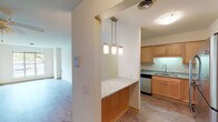 This single-floor residence offers a thoughtfully designed open-concept layout that connects the living, dining, and kitchen areas seamlessly. The kitchen is a standout feature, showcasing warm maple cabinetry, granite countertops, a classic white subway tile backsplash, and stainless steel appliances including a refrigerator, range, and over-the-range microwave. A peninsula with a granite countertop and pendant lighting serves as both a functional workspace and a casual dining area, opening directly to the living space.

The living area is generously proportioned, finished with light hardwood-style flooring and a ceiling fan, creating a bright and airy atmosphere. Large windows in multiple rooms invite natural light and provide pleasant outdoor views. The bedrooms are carpeted for comfort and offer closet space, maintaining a clean and neutral palette throughout.

The bathroom features a full tub and shower combination with white tile surround and stainless steel grab bars, reflecting an accessible and practical design. A separate bathroom includes a vanity with clean, modern finishes and tile flooring. Throughout the space, light-toned walls, consistent trim work, and a cohesive warm color scheme contribute to an inviting and functional living environment.